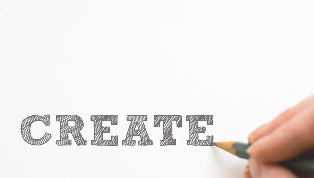hand writing the word create in large blocks with pencil
