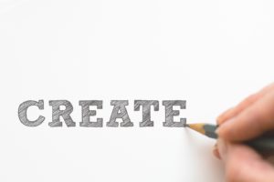 hand writing the word create in large blocks with pencil